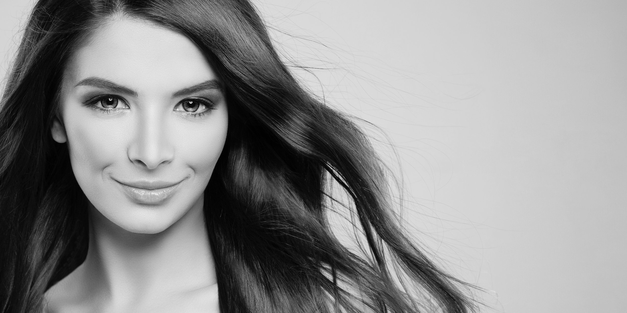 Black and white portrait of a woman with long, flowing hair, smiling softly.
